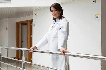 simsearch:400-06799599,k - Doctor standing at the railing smiling in hospital corridor Foto de stock - Super Valor sin royalties y Suscripción, Código: 400-06799737