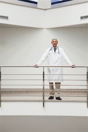 simsearch:400-06799599,k - Doctor standing at the railing of the hospital corridor smiling Foto de stock - Super Valor sin royalties y Suscripción, Código: 400-06799742