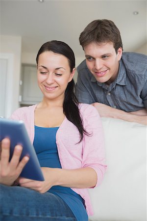 Woman sitting on the couch while using a tablet computer Stock Photo - Budget Royalty-Free & Subscription, Code: 400-06800275