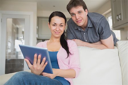 Woman sitting on the couch with a man behind her while using the tablet computer Stock Photo - Budget Royalty-Free & Subscription, Code: 400-06800273