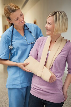 Nurse smiling with patient in arm sling in hospital corridor Stockbilder - Microstock & Abonnement, Bildnummer: 400-06800629