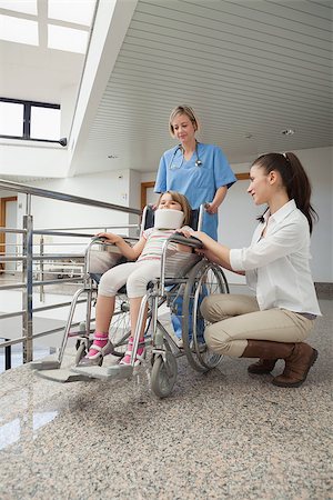 Mother crouches next to her child in wheelchair with nurse pushing it in hospital corridor Stock Photo - Budget Royalty-Free & Subscription, Code: 400-06800639