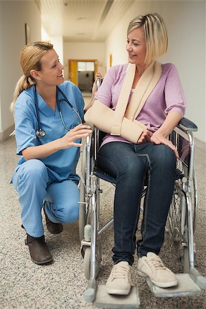 Nurse talking with patient in wheelchair with arm in sling in hospital hallway Stockbilder - Microstock & Abonnement, Bildnummer: 400-06800632