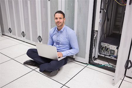 simsearch:400-06801216,k - Man sitting on floor beside servers with laptop in data center Foto de stock - Royalty-Free Super Valor e Assinatura, Número: 400-06801336