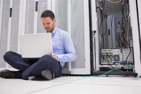 simsearch:400-06801216,k - Man sitting on floor with laptop beside servers in data center Foto de stock - Royalty-Free Super Valor e Assinatura, Número: 400-06801330