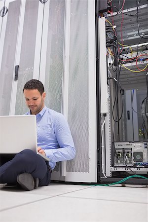 simsearch:400-06801216,k - Man working with his laptop on the floor beside servers in data center Foto de stock - Royalty-Free Super Valor e Assinatura, Número: 400-06801333