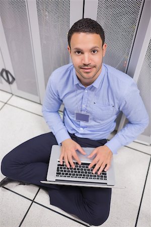simsearch:400-06801216,k - Smiling man using laptop in front of servers of data center Foto de stock - Royalty-Free Super Valor e Assinatura, Número: 400-06801341