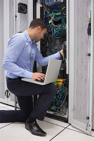 simsearch:400-06801216,k - Man fixing wires while doing maintenance with laptop in data center Foto de stock - Royalty-Free Super Valor e Assinatura, Número: 400-06801363