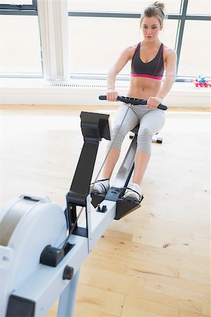 simsearch:400-06801597,k - Woman sitting at the row machine at the gym pulling Stock Photo - Budget Royalty-Free & Subscription, Code: 400-06801584