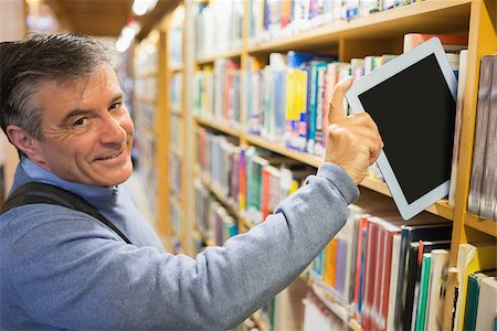 Smiling man taking a tablet pc from the shelves in library Stock Photo - Budget Royalty-Free & Subscription, Code: 400-06801636