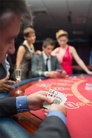 Man looking at his cards in poker game at casino Foto de stock - Super Valor sin royalties y Suscripción, Código: 400-06801815