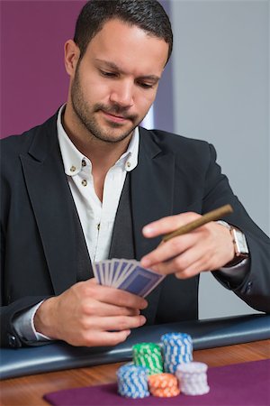 Man holding a cigar looking at his cards in casino Stock Photo - Budget Royalty-Free & Subscription, Code: 400-06801948