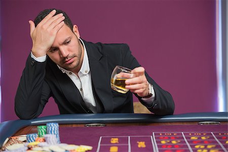 simsearch:400-06802094,k - Man looking at whiskey glass at roulette table Foto de stock - Super Valor sin royalties y Suscripción, Código: 400-06801949