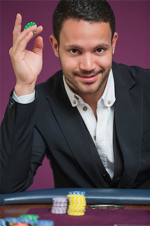 simsearch:400-06802094,k - Man sitting holding a chip between his fingers at roulette table Foto de stock - Super Valor sin royalties y Suscripción, Código: 400-06801951