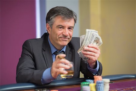 simsearch:400-06802094,k - Man holding money smiling at the roulette table in casino Foto de stock - Super Valor sin royalties y Suscripción, Código: 400-06801961