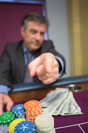 simsearch:400-06802091,k - Man with chips and cash pointing sitting at roulette table Stock Photo - Budget Royalty-Free & Subscription, Code: 400-06801963