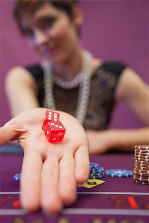 Woman sitting in a casino at table holding dices while smiling Stock Photo - Budget Royalty-Free & Subscription, Code: 400-06802038