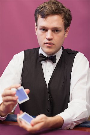 Dealer sitting at table of a casino while shuffling a deck of cards Stock Photo - Budget Royalty-Free & Subscription, Code: 400-06802054