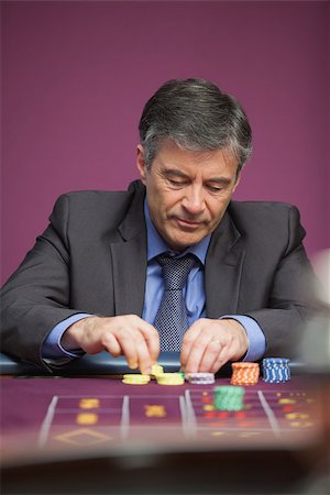 simsearch:400-06802091,k - Man grabbing chips while playing roulette and sitting at table in a casino Stock Photo - Budget Royalty-Free & Subscription, Code: 400-06802087