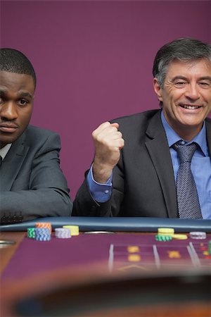 simsearch:400-06802091,k - Smiling man sitting at table in a casino and celebrating roulette win Stock Photo - Budget Royalty-Free & Subscription, Code: 400-06802089