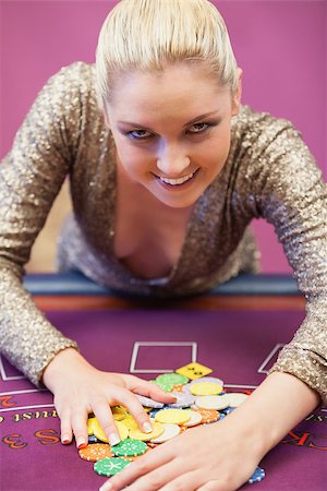 Winning woman standing at table in a casino and grabbing chips while smiling Stock Photo - Budget Royalty-Free & Subscription, Code: 400-06802080