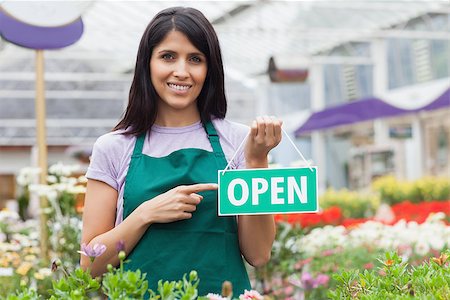 employee hold a sign - Woman in garden center pointing at the open-sign while smiling Stock Photo - Budget Royalty-Free & Subscription, Code: 400-06802532