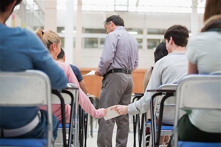 passing of papers in the classroom - Students passing a note behind teacher's back in classroom Stock Photo - Budget Royalty-Free & Subscription, Code: 400-06803100