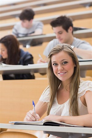 simsearch:400-06803206,k - Woman sitting while smiling at the lecture hall and taking notes Stock Photo - Budget Royalty-Free & Subscription, Code: 400-06803197