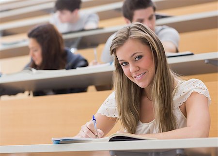 simsearch:400-06803206,k - Woman sitting at the lecture hall while smiling and writing notes Stock Photo - Budget Royalty-Free & Subscription, Code: 400-06803198