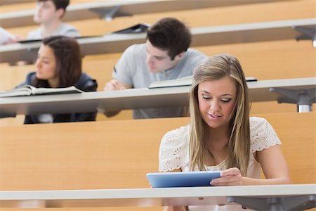 student in lecture hall - Student sitting at the lecture hall while holding a tablet pc and usig it to take notes Stock Photo - Budget Royalty-Free & Subscription, Code: 400-06803206