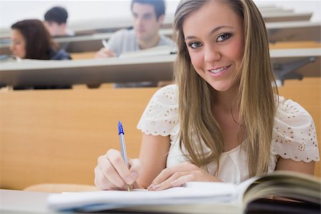 simsearch:400-06803206,k - Woman sitting at the lecture hall while writing and smiling Stock Photo - Budget Royalty-Free & Subscription, Code: 400-06803201