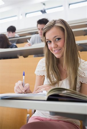 simsearch:400-06803206,k - Woman sitting at the lecture hall holding a pen while smiling Stock Photo - Budget Royalty-Free & Subscription, Code: 400-06803202