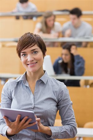 simsearch:400-06803206,k - Woman standing holding a tablet computer smiling at the lecture hall Stock Photo - Budget Royalty-Free & Subscription, Code: 400-06803226