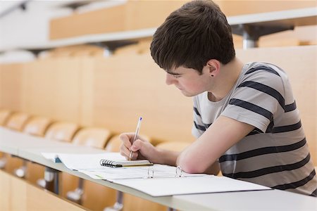 simsearch:400-06803206,k - Student sitting at the lecture hall while writing on notepad Stock Photo - Budget Royalty-Free & Subscription, Code: 400-06803256