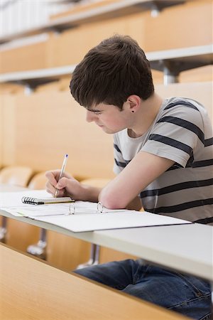 simsearch:400-06803206,k - Concentrated student sitting at the lecture hall while writing Stock Photo - Budget Royalty-Free & Subscription, Code: 400-06803257