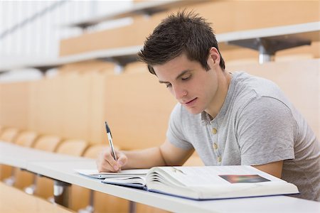simsearch:400-06803206,k - Student sitting reading a book and taking notes in lecture hall Stock Photo - Budget Royalty-Free & Subscription, Code: 400-06803251