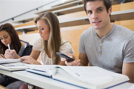 simsearch:400-06803206,k - Students sitting at the desk learning with one man holding a smartphone Stock Photo - Budget Royalty-Free & Subscription, Code: 400-06803267