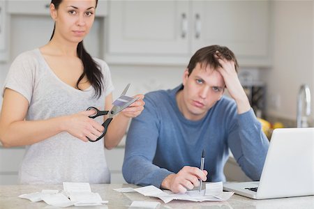 simsearch:400-06803524,k - Disappointed couple in the kitchen cutting credit card and looking at finances on laptop Stock Photo - Budget Royalty-Free & Subscription, Code: 400-06803536
