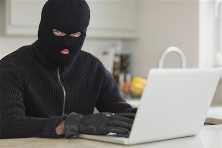 simsearch:400-06803573,k - Burglar using laptop sitting in kitchen Stock Photo - Budget Royalty-Free & Subscription, Code: 400-06803554