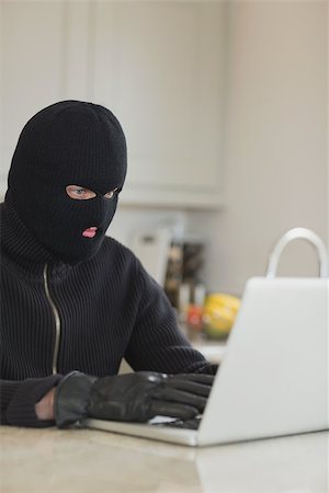 simsearch:400-06803573,k - Robber sitting in the kitchen hacking laptop Stock Photo - Budget Royalty-Free & Subscription, Code: 400-06803552