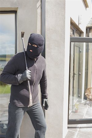 Burglar hiding behind wall with crow bar in back garden Stockbilder - Microstock & Abonnement, Bildnummer: 400-06803572