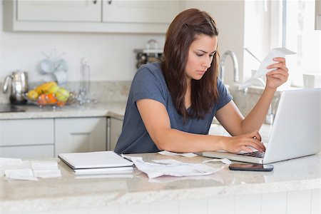 simsearch:400-06803524,k - Woman holding a bill while calculating on the laptop Stock Photo - Budget Royalty-Free & Subscription, Code: 400-06803676
