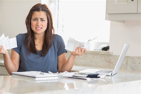 simsearch:400-06803524,k - Woman looking troubled while holding bills in the kitchen Stock Photo - Budget Royalty-Free & Subscription, Code: 400-06803670