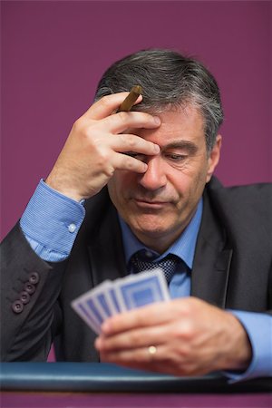 simsearch:400-06802091,k - Man holding his cards thinking while holding a cigar Stock Photo - Budget Royalty-Free & Subscription, Code: 400-06803710