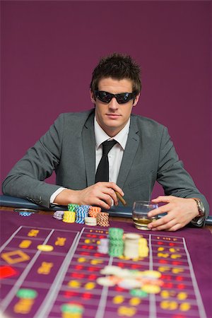 Man wearing sun glasses at roulette table drinking whiskey and smoking cigar Photographie de stock - Aubaine LD & Abonnement, Code: 400-06803722