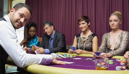people sitting in casino - Dealer smiling at poker game in casino Stock Photo - Budget Royalty-Free & Subscription, Code: 400-06803738