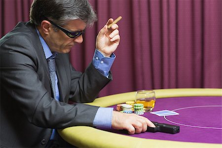 simsearch:400-06802091,k - Man wearing sun glasses with gun at poker table in casino Stock Photo - Budget Royalty-Free & Subscription, Code: 400-06803757