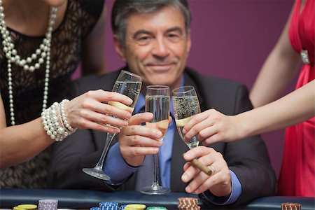 simsearch:400-06802094,k - Smiling man sitting at the casino while clinking glasses with women Foto de stock - Super Valor sin royalties y Suscripción, Código: 400-06803794
