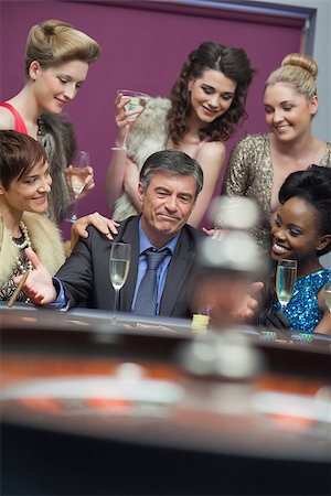 Man surrounded by women accepting of loss in casino Foto de stock - Super Valor sin royalties y Suscripción, Código: 400-06803817