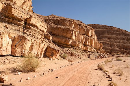 A dirt road, marked with stones; follows a line of rocky cliffs through the Negev Desert in the southern portion of Israel Stock Photo - Budget Royalty-Free & Subscription, Code: 400-06857417